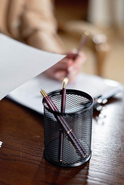 Stylos et documents sur un bureau en bois pour préparer un rendez-vous chez le notaire