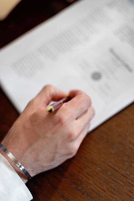 Signature de l'acte authentique de vente sur une table en bois chez le notaire